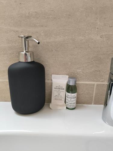 a black soap dispenser sitting on a bathroom sink at Hyper Centre Beauvais Cosy Appartement in Beauvais