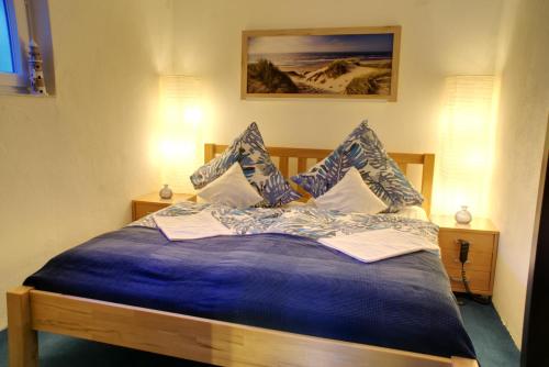 a bed with a blue comforter and pillows at Gästehaus Wildblume in Borgdorf-Seedorf