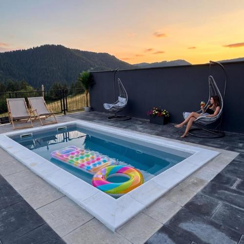 a woman sitting in a chair next to a swimming pool at Weekend house - Vlašić in Vlasic