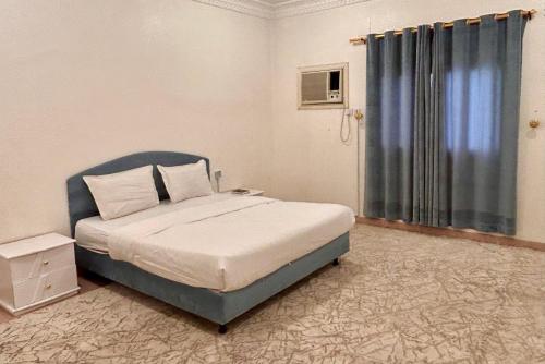 a bedroom with a bed with a blue headboard and a window at الكرامة للشقق المفروشة in Abha