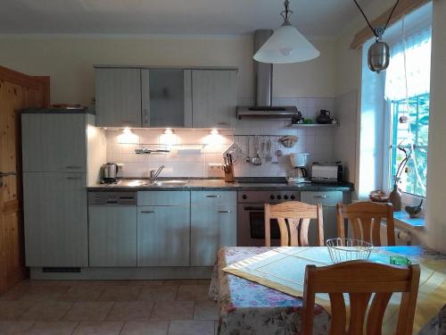 a kitchen with gray cabinets and a table and a dining room at Tannenblick Loppin EG in Jabel