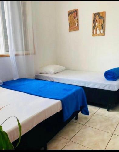 two beds in a room with blue and white at Pousada Encanto De Itanhaém in Itanhaém