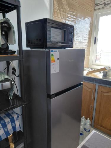 a microwave on top of a refrigerator in a kitchen at Résidence Al-amine in Koungou
