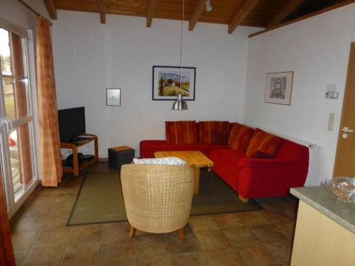 a living room with a red couch and a tv at Ferienhaus Jabel 24 in Jabel