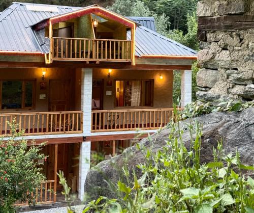 a log cabin with a balcony on a rock at GhratFalls Stone Cottage in Banjār