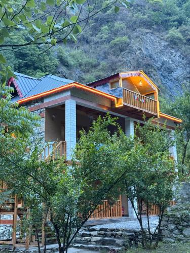 a house with a wrap around porch and a deck at GhratFalls Stone Cottage in Banjār
