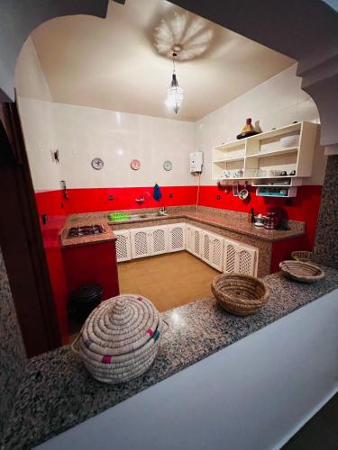 a kitchen with red walls and baskets on the counter at Zakar Apartments & Terrace in Mirleft