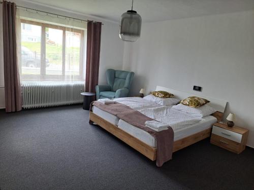 a bedroom with a bed and a chair and a window at Apartmán PASOMA in Levoča