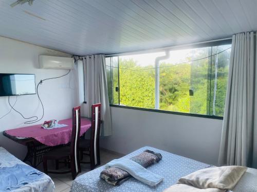 a room with a window and a table and a table and a bed at Hostel Meu Sossego Vilas in Lauro de Freitas