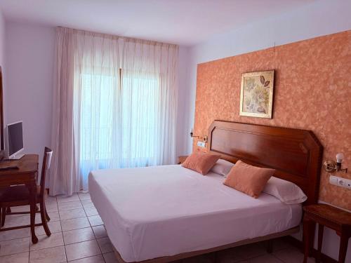 a bedroom with a bed and a desk and a window at Hotel Alandalus in Torrox