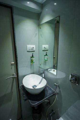 ein Badezimmer mit einem weißen Waschbecken und einem Spiegel in der Unterkunft HOTEL AMBER PARAMOUNT in Mumbai