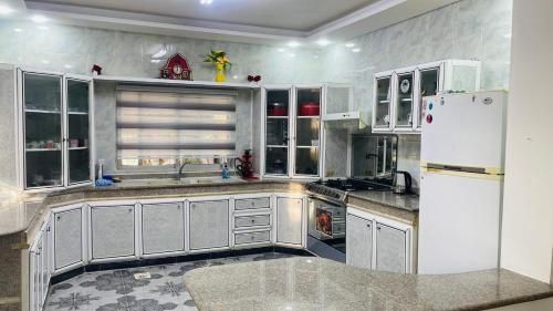 a kitchen with white cabinets and a white refrigerator at Mountain View House- بيت إطلالة الجبل in Ajloun