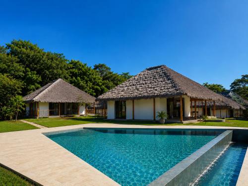 a villa with a swimming pool in front of a house at ITAMPOLO Suites & Lodges in Nosy Be
