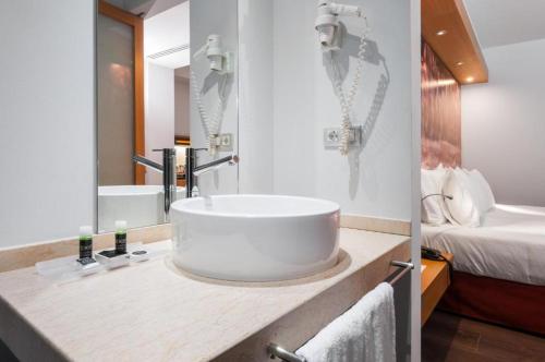 a bathroom with a large white sink and a bed at VM Princep in Andorra la Vella