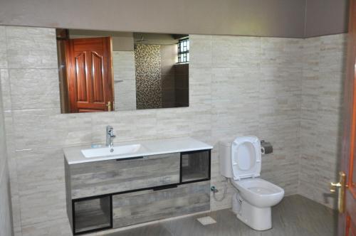 a bathroom with a sink and a toilet and a mirror at Majimbo Whitehouse Resort in Ramogi