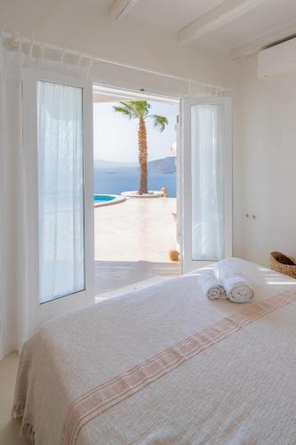 a white bedroom with a view of the ocean at Villa Achilleas Crete in Ierapetra