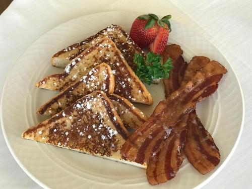 a white plate with french toast and a strawberry at The Oaks Waterfront Hotel in Saint Michaels