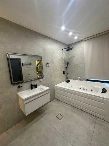 a bathroom with a tub and a sink and a mirror at Trio Luxury Apartment 3 in Sowayma