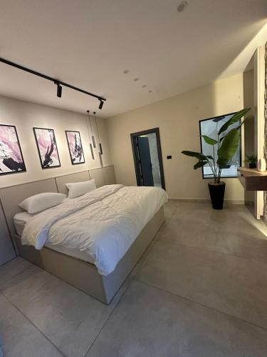 a bedroom with a large bed and a potted plant at Trio Luxury Apartment 3 in Sowayma