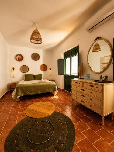 a bedroom with a bed and a table and a mirror at Encanto Guesthouse in Canillas de Aceituno