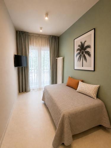 a bedroom with a bed with a palm tree picture on the wall at Residence Danio in Alassio