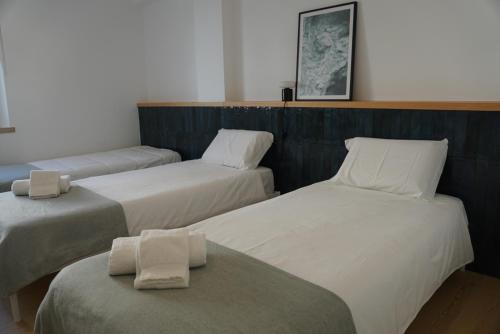 a room with three beds with towels on them at Alfaiate Beach House in Santa Cruz