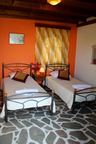 two beds in a room with orange walls at Dimitra Studios in Kastraki Naxou