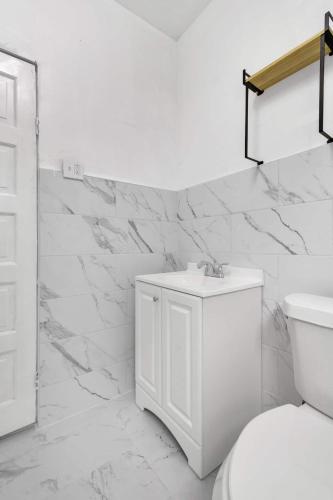 a white bathroom with a toilet and a sink at 5-Bed Home Game Room Pool Table Sleeps 13 in Buffalo