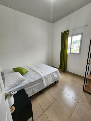 a bedroom with a bed with white sheets and a window at Marsella Rest House in Sitio del Niño