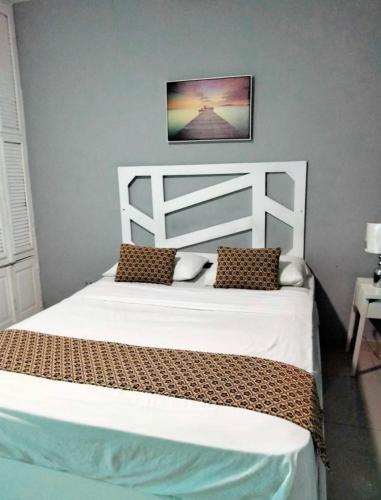 a bedroom with a white bed with two pillows at Sunshine Hotel - Puerto Plata in San Felipe de Puerto Plata
