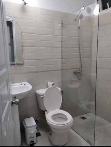 a bathroom with a shower and a toilet and a sink at Sunshine Hotel - Puerto Plata in San Felipe de Puerto Plata