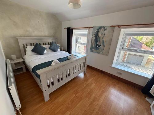 a bedroom with a white bed and two windows at The Millstone in Buncrana