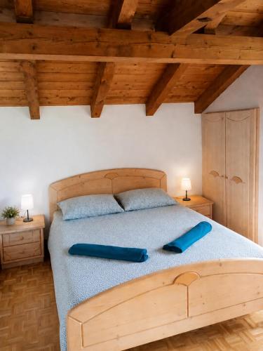 a bedroom with a wooden bed with two blue pillows at APPARTAMENTO ROEN - Val di Non in Cavareno