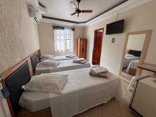 two beds in a room with a mirror and a room with two beds at Hospedaria Monumento in São Paulo