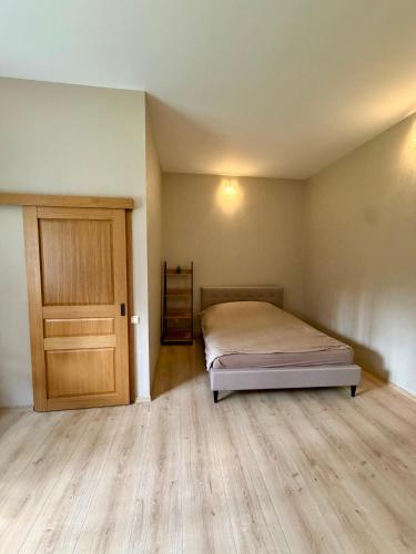 a bedroom with a bed and a wooden door at Männimetsa in Narva-Jõesuu