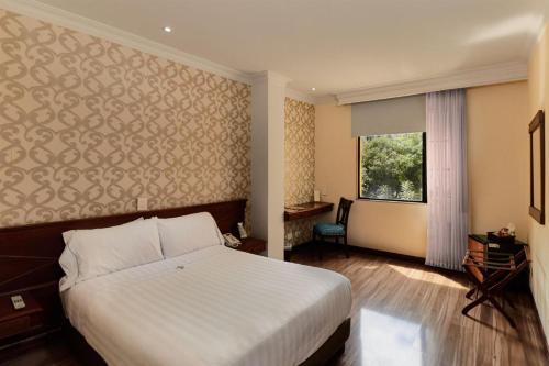 a bedroom with a white bed and a window at Hotel Castilla Real in Pereira