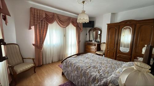 a bedroom with a bed and a chair and a window at Grandma Luísa's Corner in Verdelhos