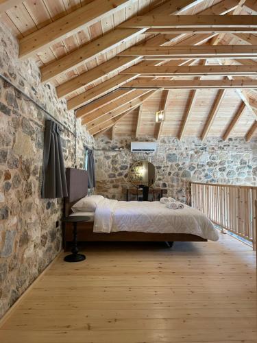 a bedroom with a bed and a stone wall at Mesovouni Stone Suites 1 in Mesovounion-Zagori
