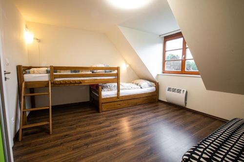 a attic room with two bunk beds and a window at Wellness Hotel Říčky in Říčky
