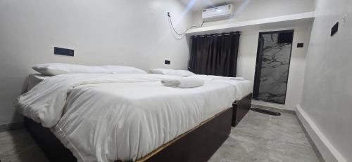 a bedroom with two beds with white sheets at Tuljapur Bhaktaniwas in Tuljapur