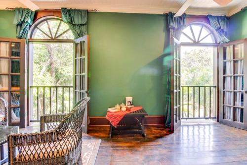 a green room with a table and two windows at Colonial Suite @ Mahogany Hall in San Ignacio