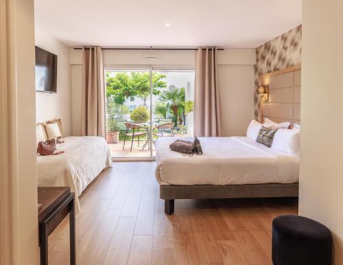 a hotel room with two beds and a balcony at Hôtel La Villa Cannes in Cannes
