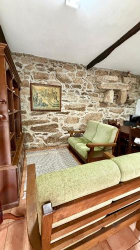 a bedroom with a stone wall with a bed and chairs at Casa da Adega in Sá