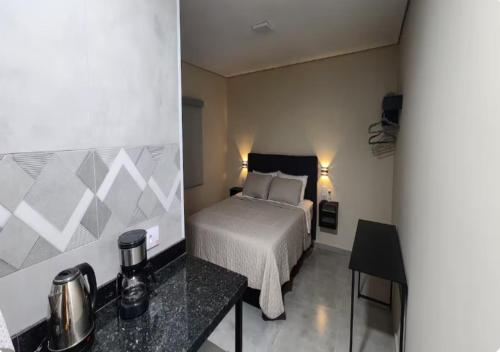 a bedroom with a bed and a table in a room at Pousada Rainha da Serra in Espirito Santo Do Pinhal