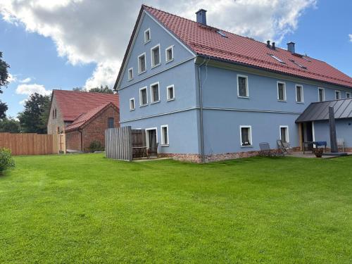 a large white house with a green yard at Agroturystyka Muraszkowa Zagroda in Giebułtów