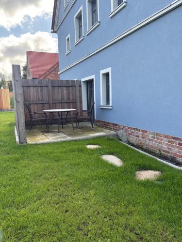 a patio with a picnic table next to a blue building at Agroturystyka Muraszkowa Zagroda in Giebułtów