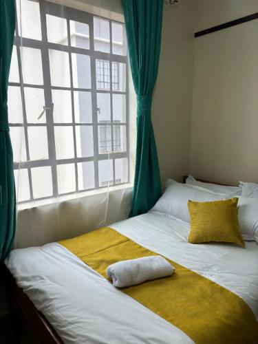 a bed with a yellow blanket and a window at Prestige apartments Machakos in Machakos