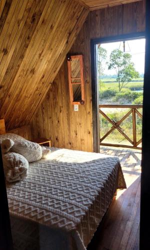 a bedroom with a bed and a large window at Cabanas Brisa da Lagoa in Arroio do Silva