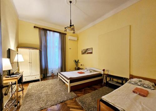 a room with two beds and a desk and a window at Cricket 2 Hostel in Belgrade