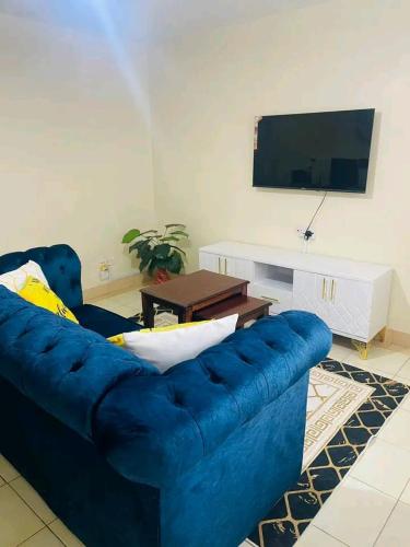 a blue couch in a living room with a tv at Bulleys BNB in Thika